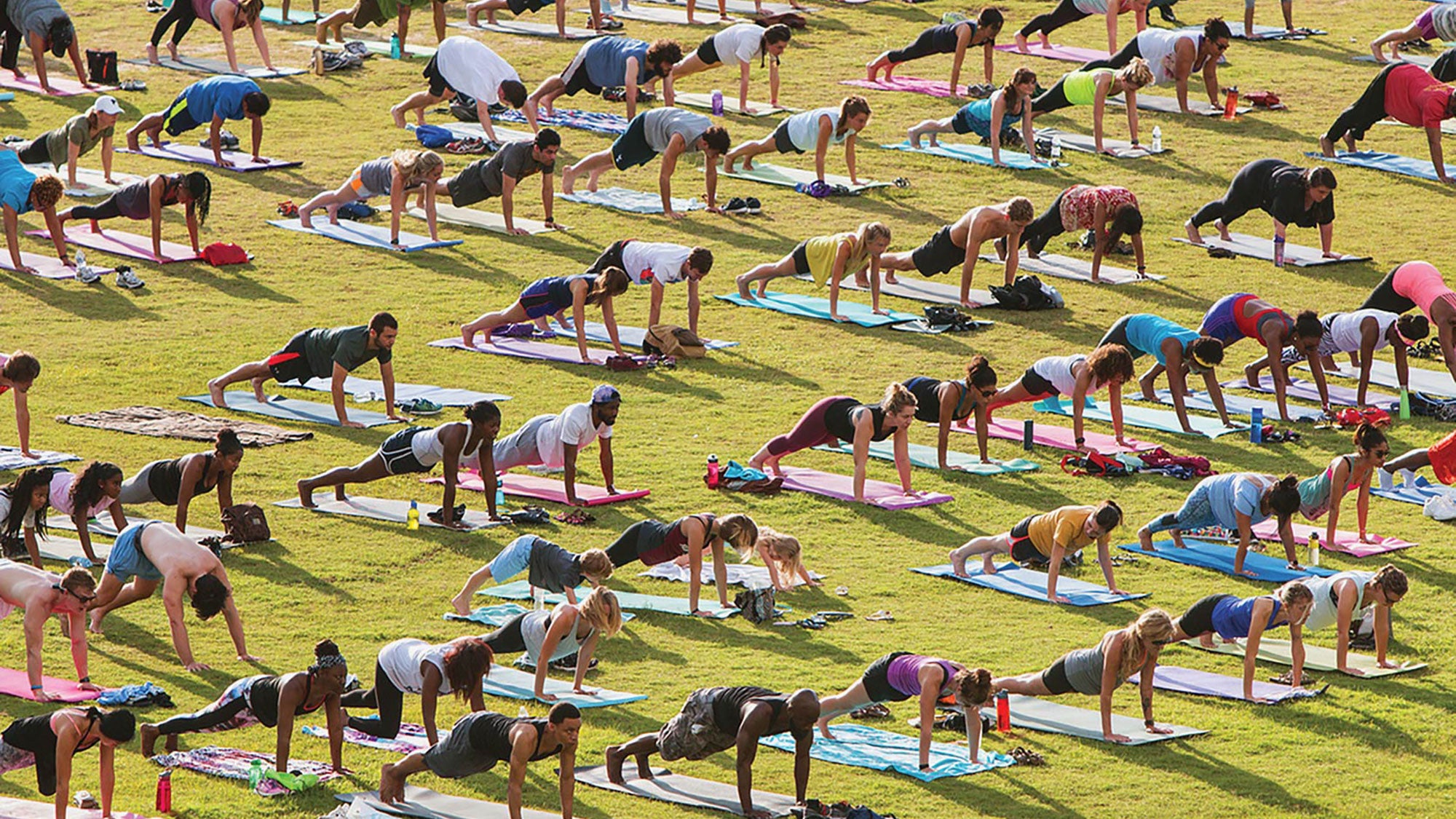 Mange mennesker gjør yoga i et felt av gress