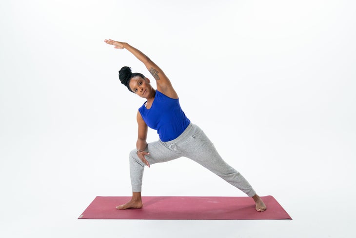 A person demonstrates Extended Side Angle Pose (Utthita Parsvakonasana) with her forearm resting on her thigh