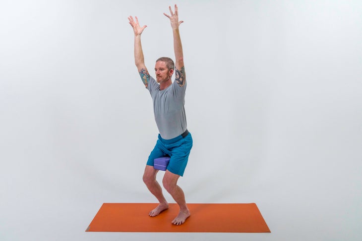 A person demonstrates a variation of Chair Pose (Utkatasana) in yoga