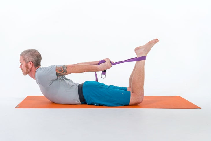 A person demonstrates a variation of Bow Pose using a strap around their legs