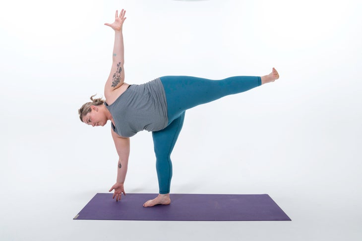 Woman practices Half Moon Pose