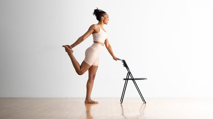 Woman in Dancer Pose variation holding on to a chair