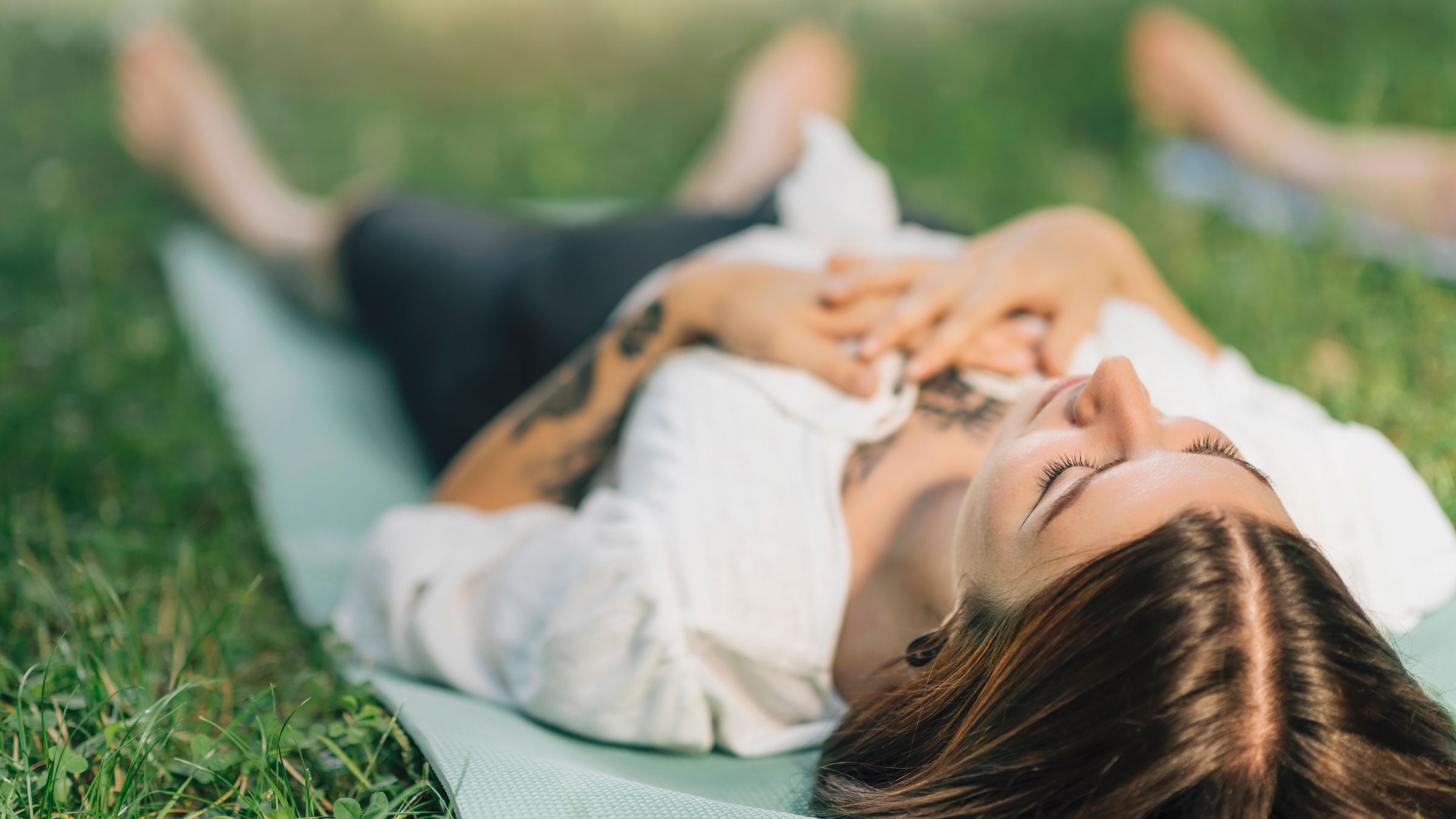Woman lying down on grass with eyes closed