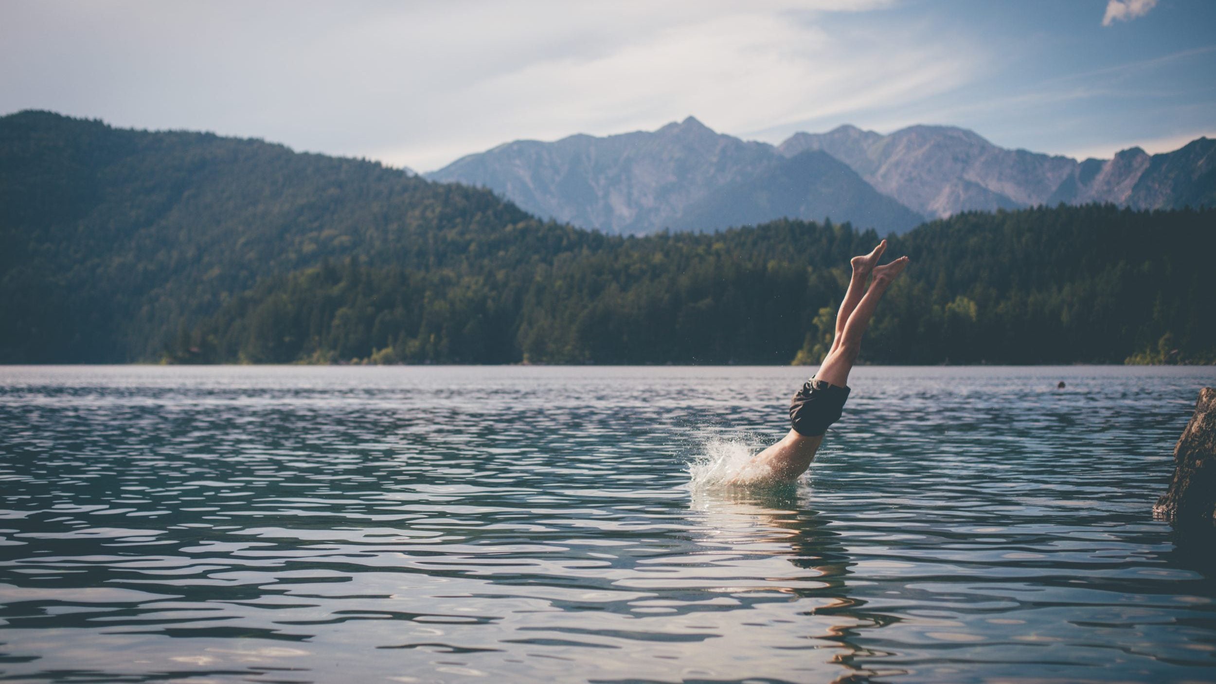 A man jumps into a mountain lake