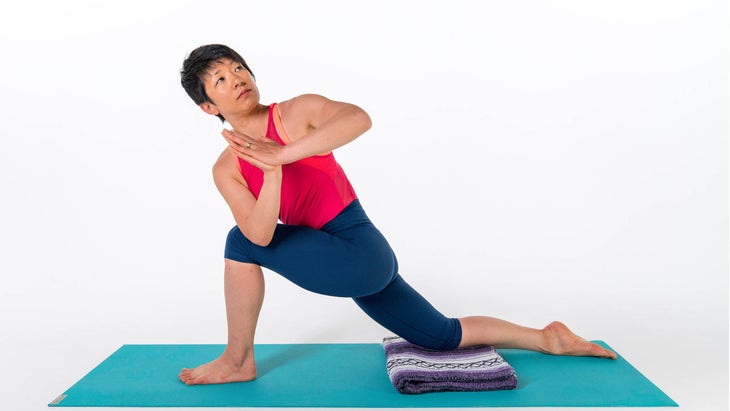 A woman demonstrates a variation of Revolved Side Angle with her back knee down