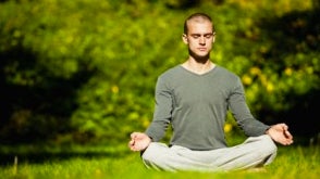 Man meditating on grass outside