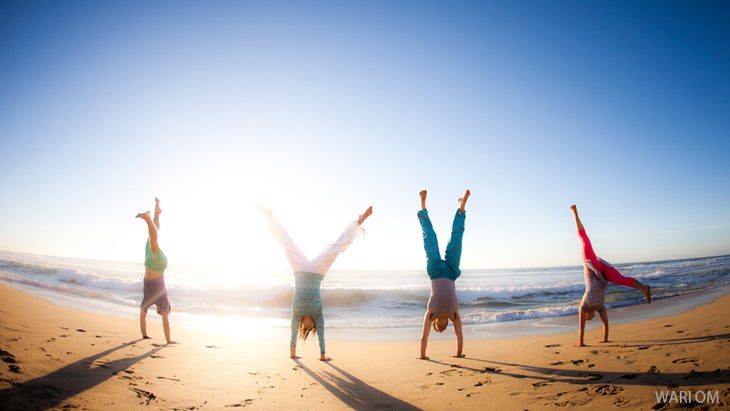 yogis doing inversions on a beach yogis doing inversions on a beach