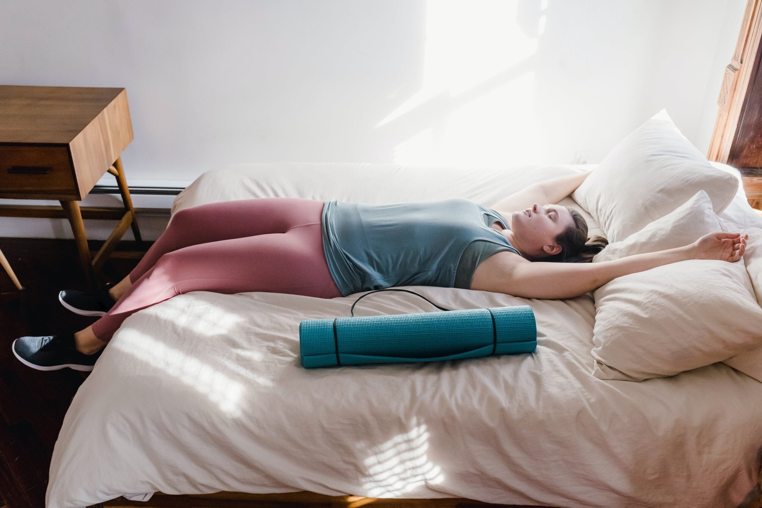Woman practicing restorative yoga on bed.