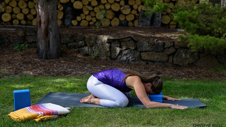 Deven Sisler performs Child’s Pose with a block. Deven Sisler performs Child’s Pose with a block.