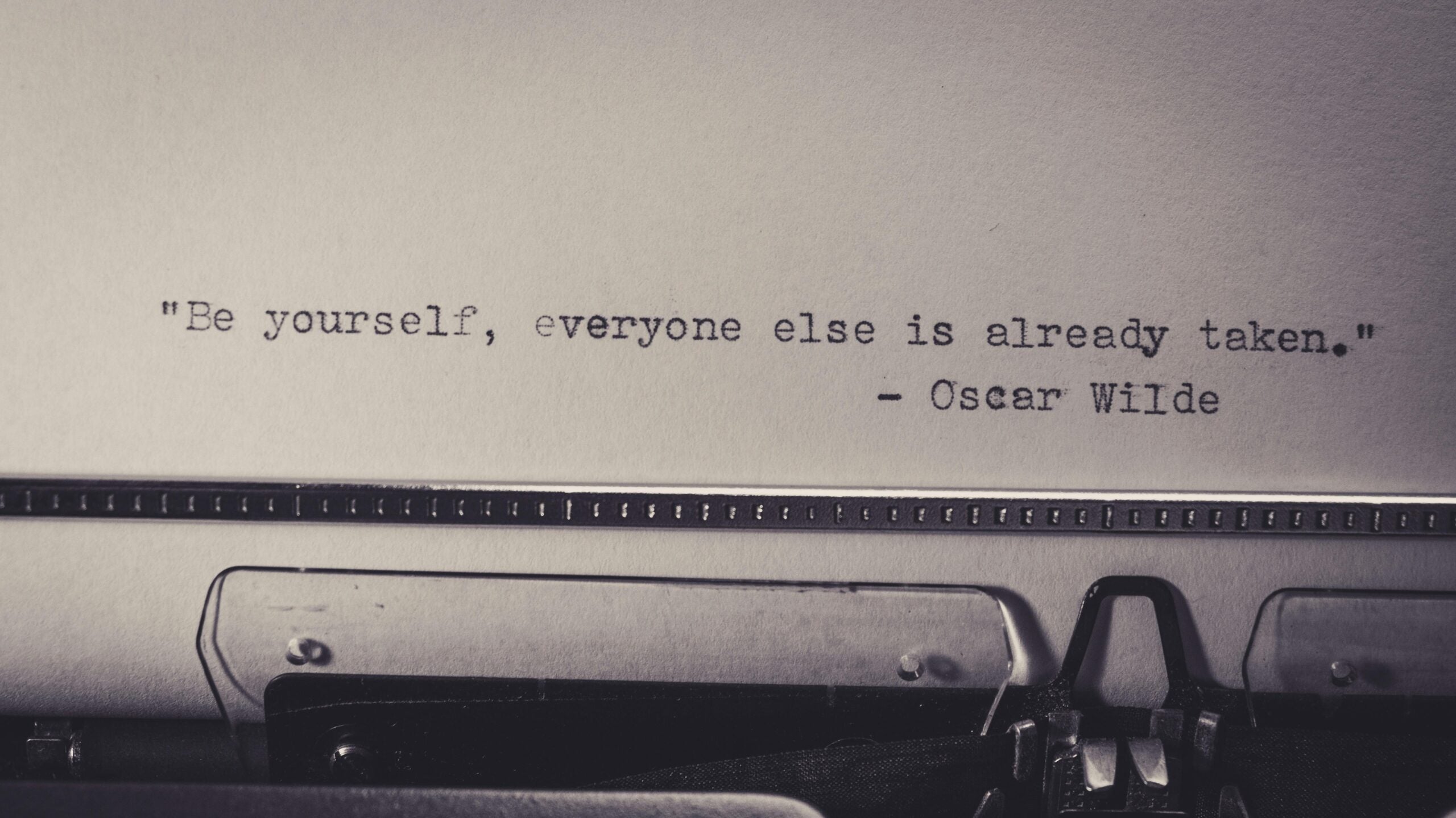 Image of a typewriter with a blank page in it, on which is written "Be Yourself, Everyone Else Is Already Taken. Oscar Wilde."