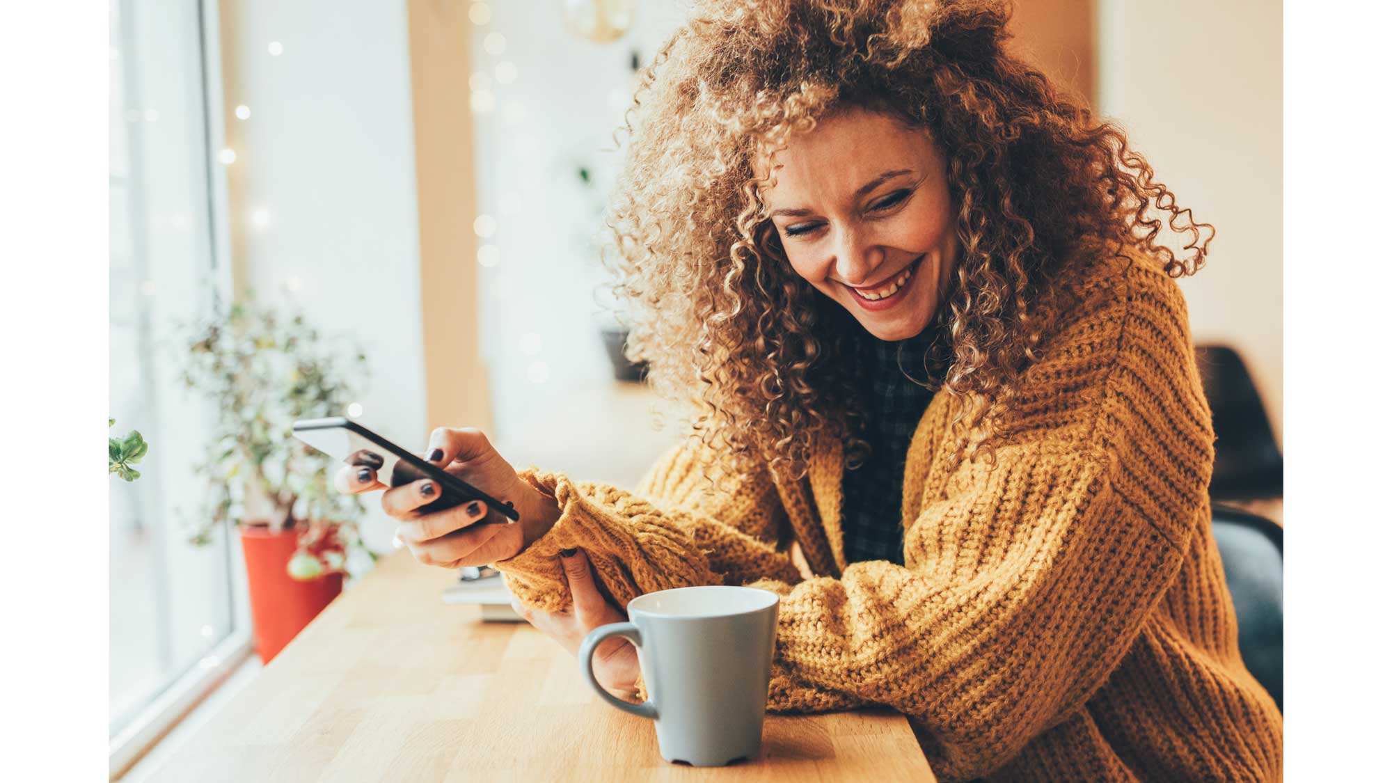 Woman smiling drinking coffee on phone
