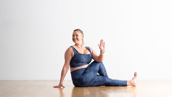 Woman seated on the floor practicing a twist known as Half Lord of the Fishes in yoga