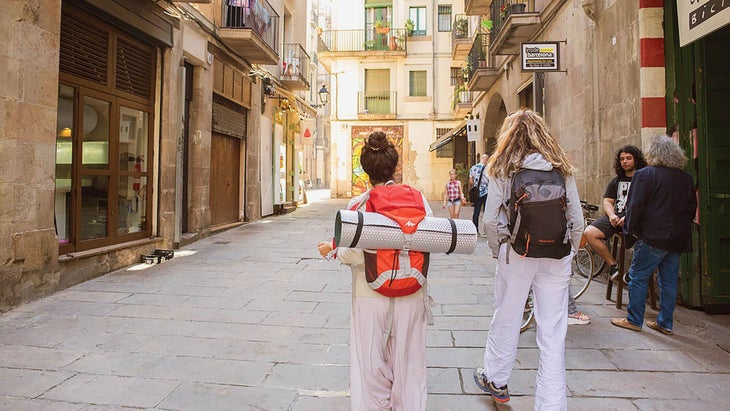 Resized-TravelDest_309_896254326_bjk Two women wearing backpacks walking down a street between old stone buildings