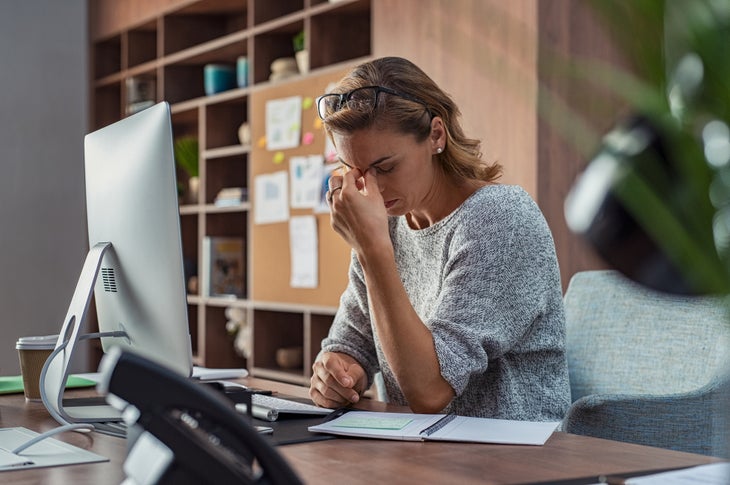 Exhausted businesswoman having a headache in modern office.