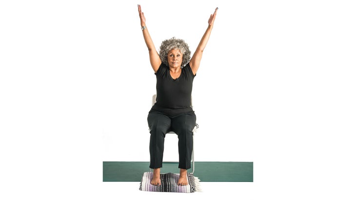 Front shot of woman in a chair with both arms raised