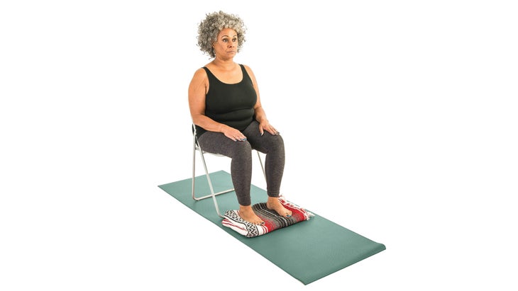 Woman sitting upright in chair with hands on thighs