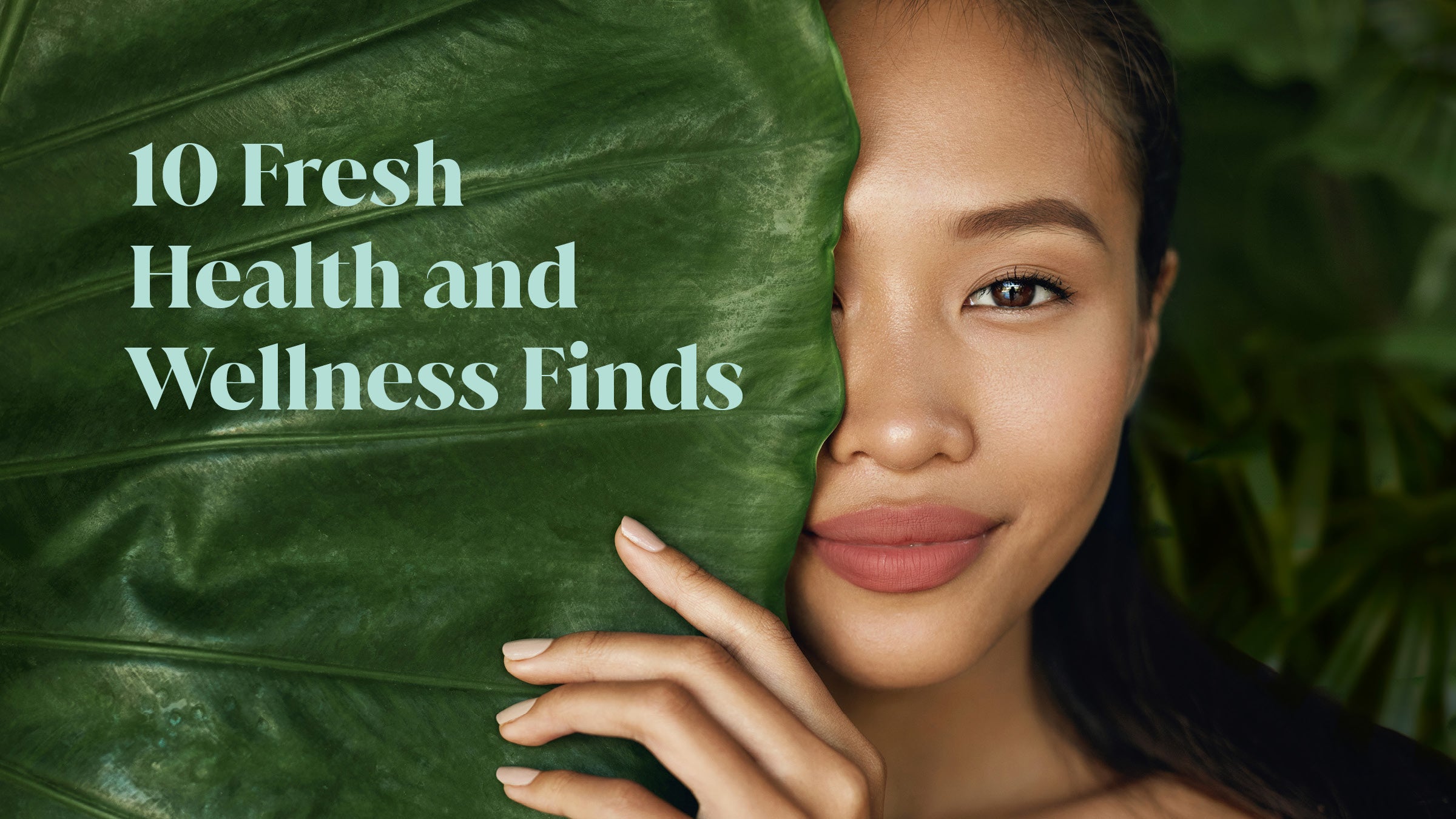 Smiling woman hides half her face behind large plant leaf