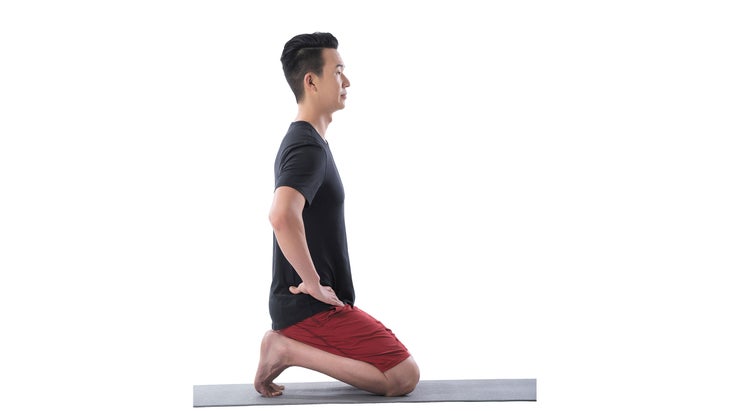 A man performs a kneeling toe stretch in yoga