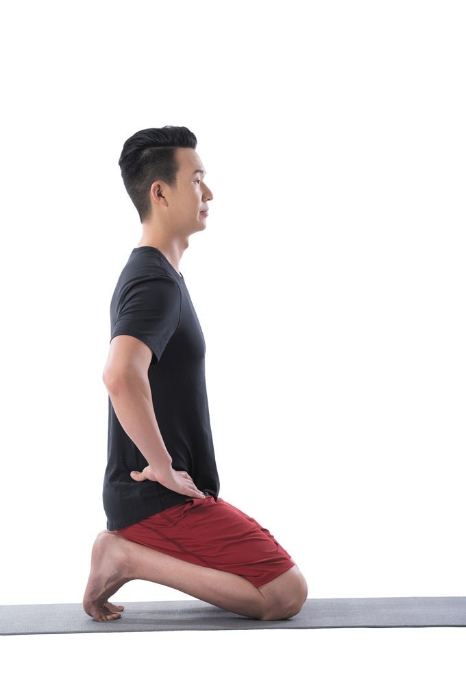 A man performs a kneeling toe stretch in yoga