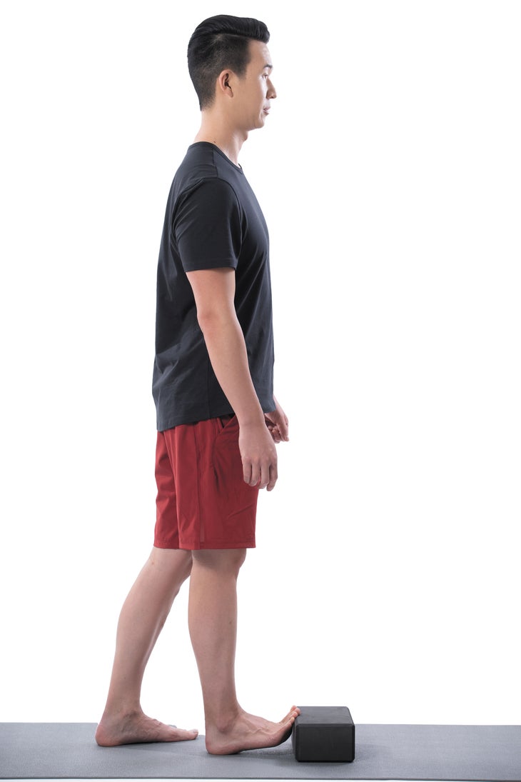 A man performs a standing toe stretch