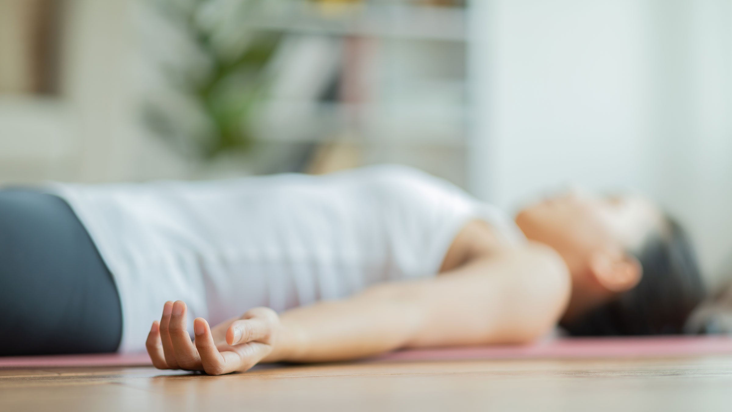 A woman lays in Savasana (Corpse Pose) during a Yoga Nidra practice