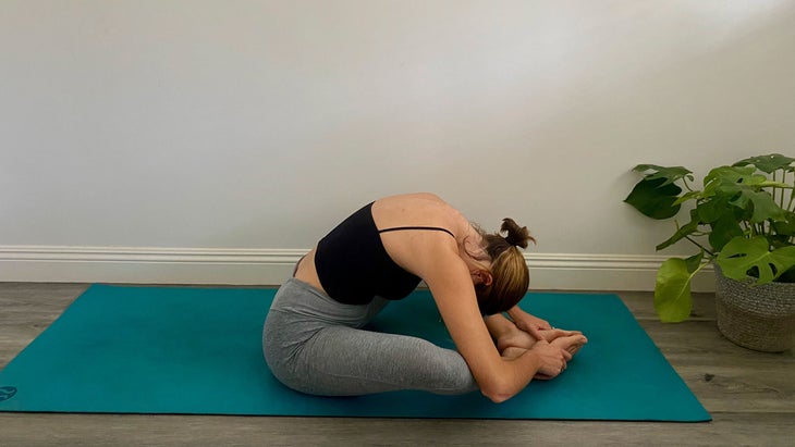 A woman demonstrates Bound Angle pose