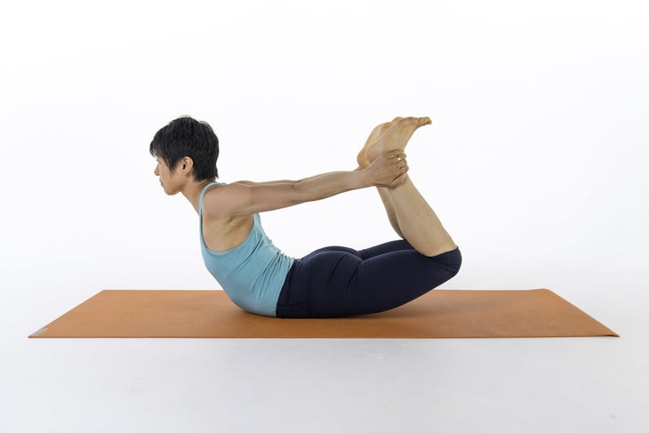 A woman demonstrates Dhanurasana (Bow Pose) in yoga