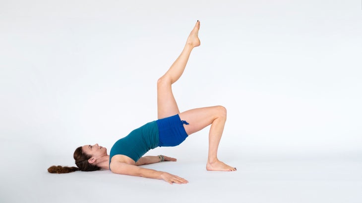 A woman demonstrates Setu Bandha Sarvangasana, variation (Bridge Pose)