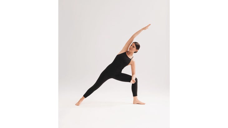 A woman wearing black demonstrates Utthita Parsvakonasana (Extended Side Angle Pose) in yoga