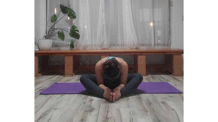 A person performs Baddha Konasana (Bound Angle Pose)