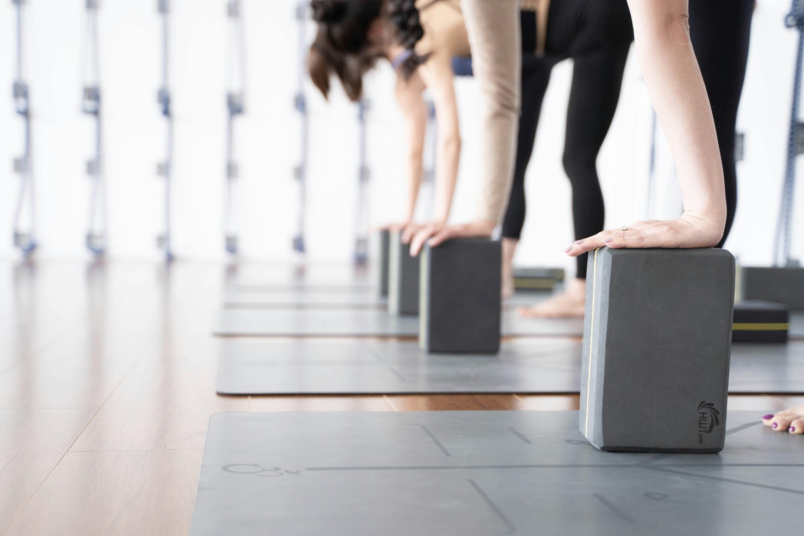 Image of people in yoga class with their hands on blocks.