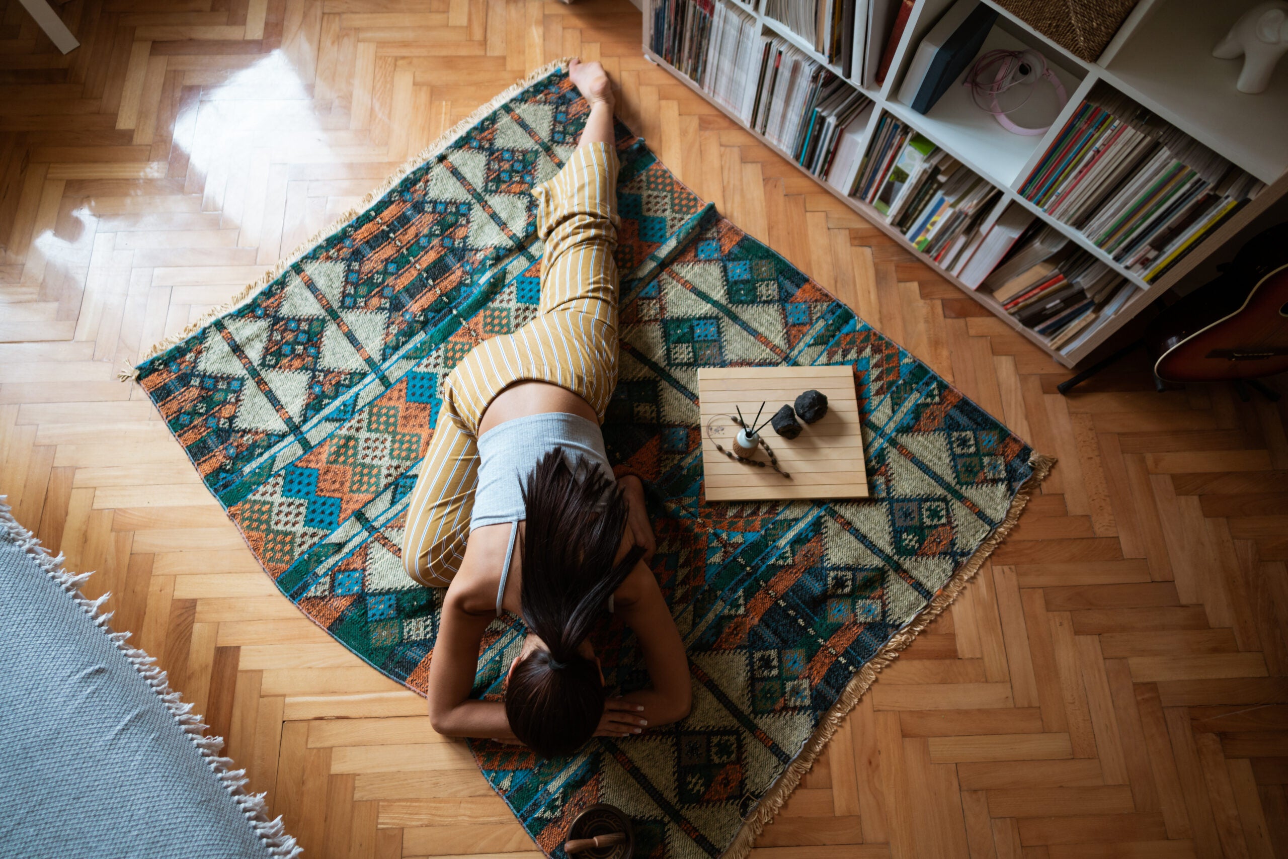 Woman doing pigeon pose at home on a blanket.