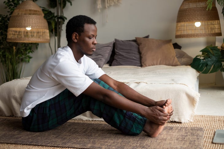 Black man in green pants, in paschimoytanasana