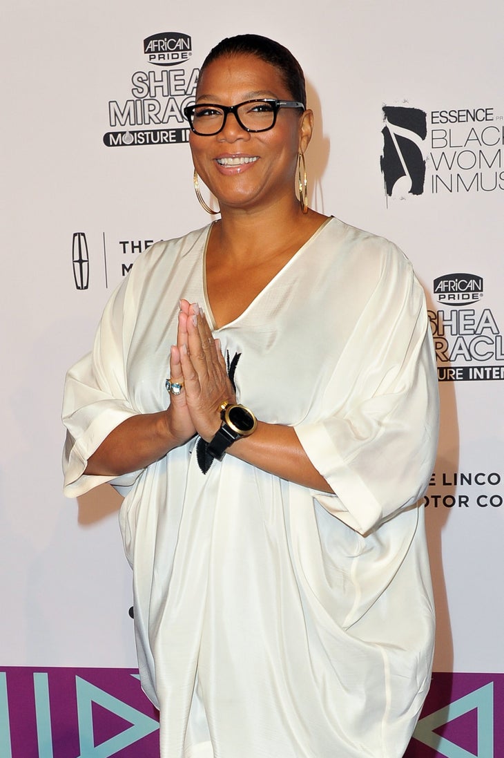 Actor/rapper Queen Latifah in a white top and dark pants holds her hands in a prayer position