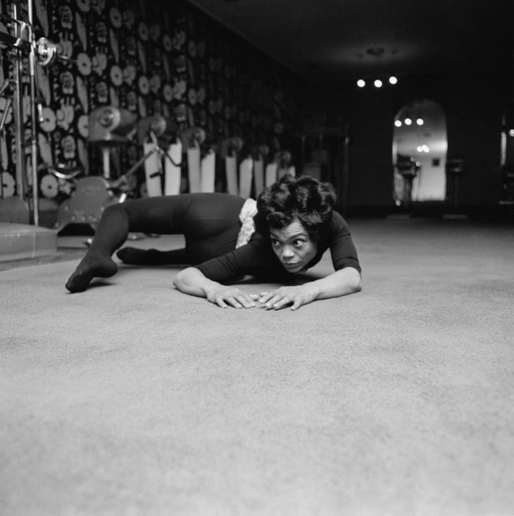 Actor and singer Eartha Kitt in dark leotard and tights practices a complicated twist