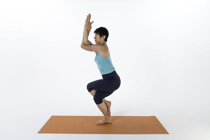Asian Woman in blue clothes doing Garudasana