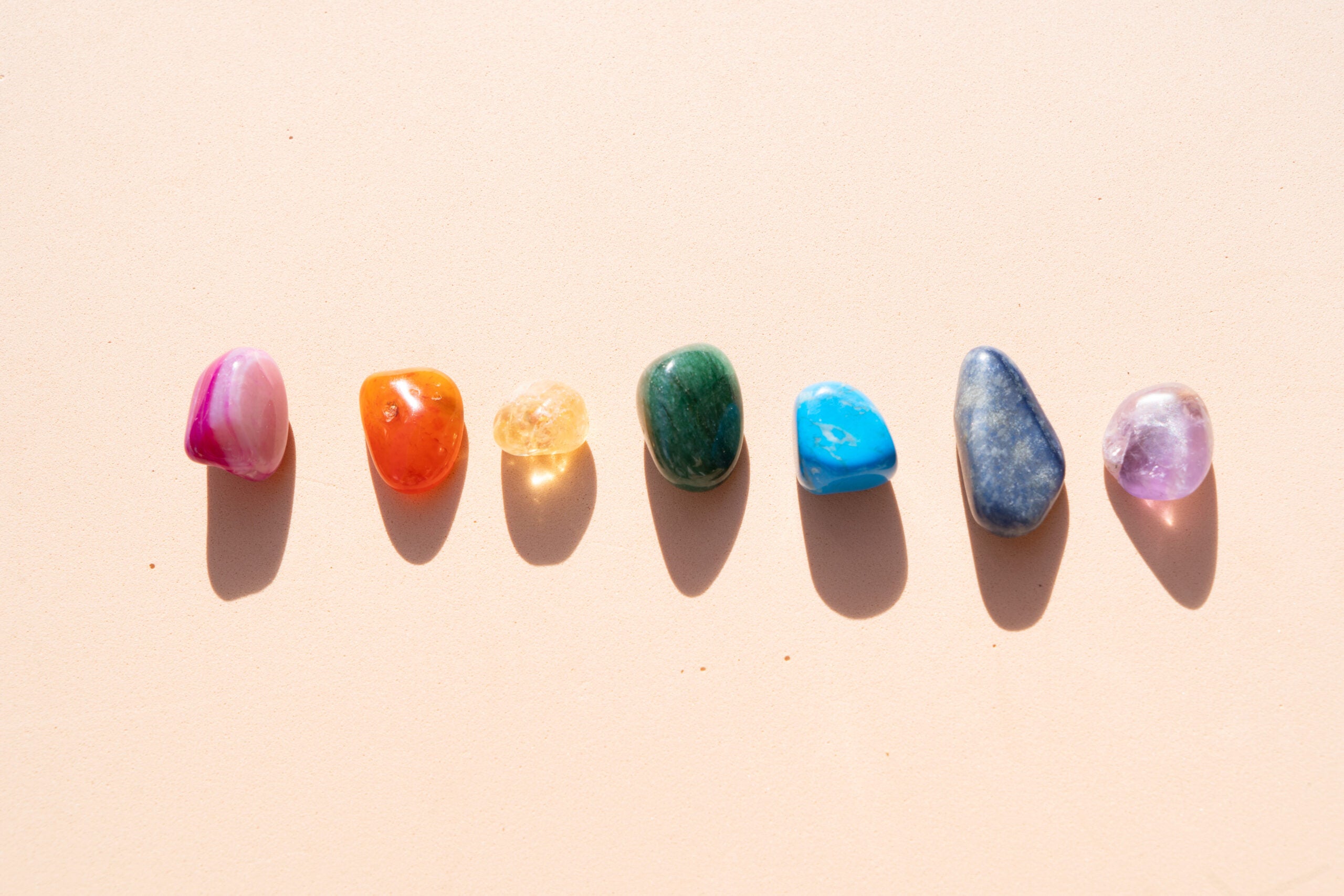 Rainbow colored healing crystals on an offwhite background