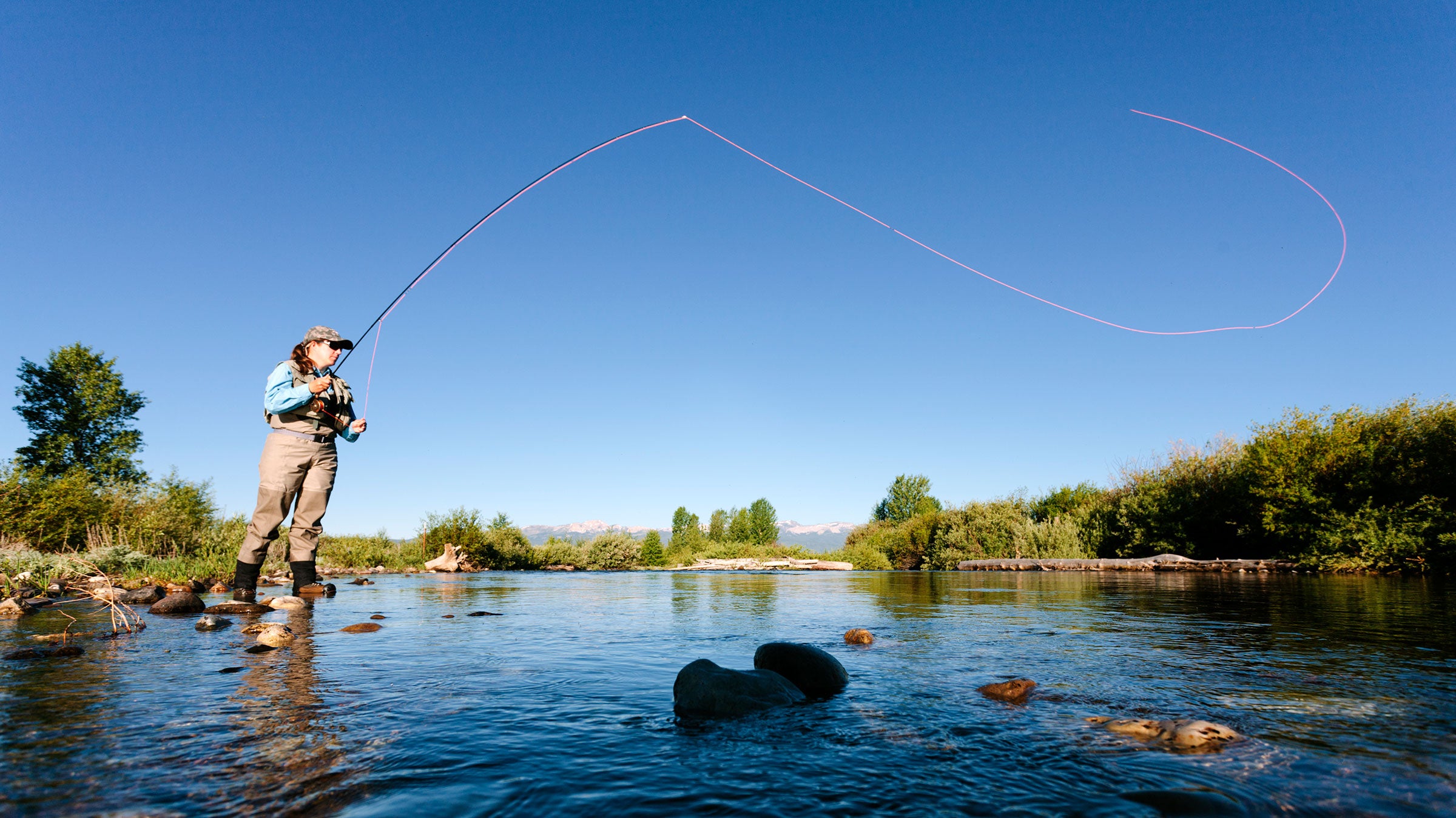 A woman fly-fishing in a river