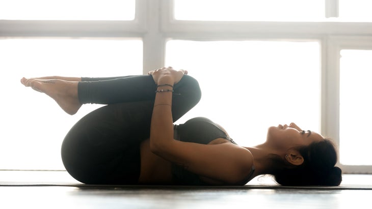 A woman demonstrates Knee-to-Chest Pose in yoga