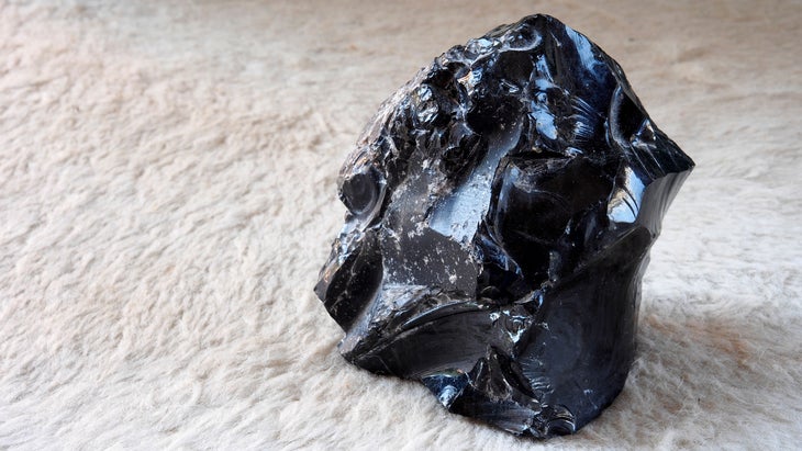 Black obsidian is pictured on a white textured background