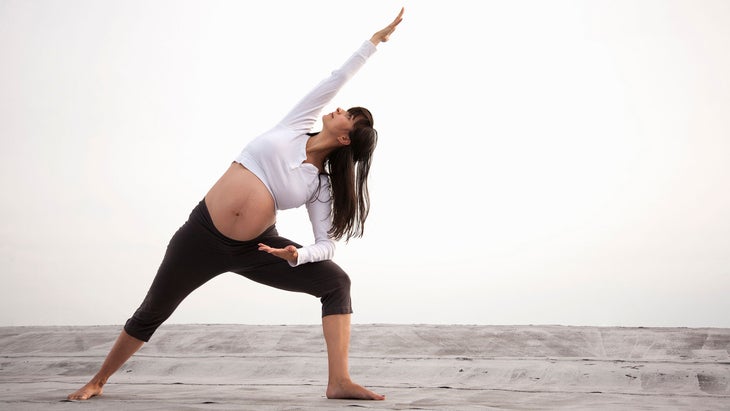 A woman does extended side angle pose during pregnancy