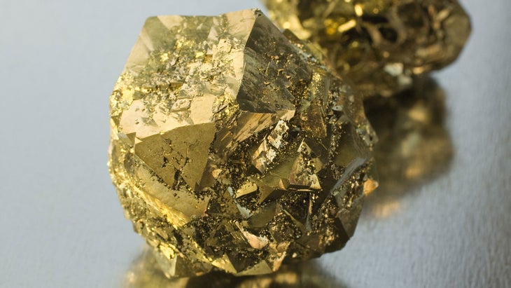 Two gold pyrite crystals are pictured up close