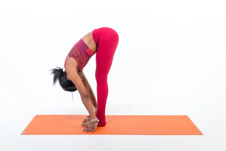 A woman practices Uttanasana (Standing Forward Bend) in yoga