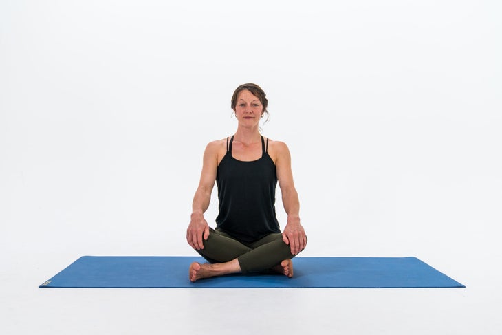 A woman sits in Sukhasana (Easy Pose), a yoga pose for beginners