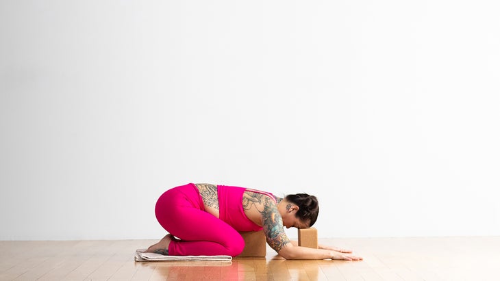 Woman demonstrating Child's Pose with a bolster
