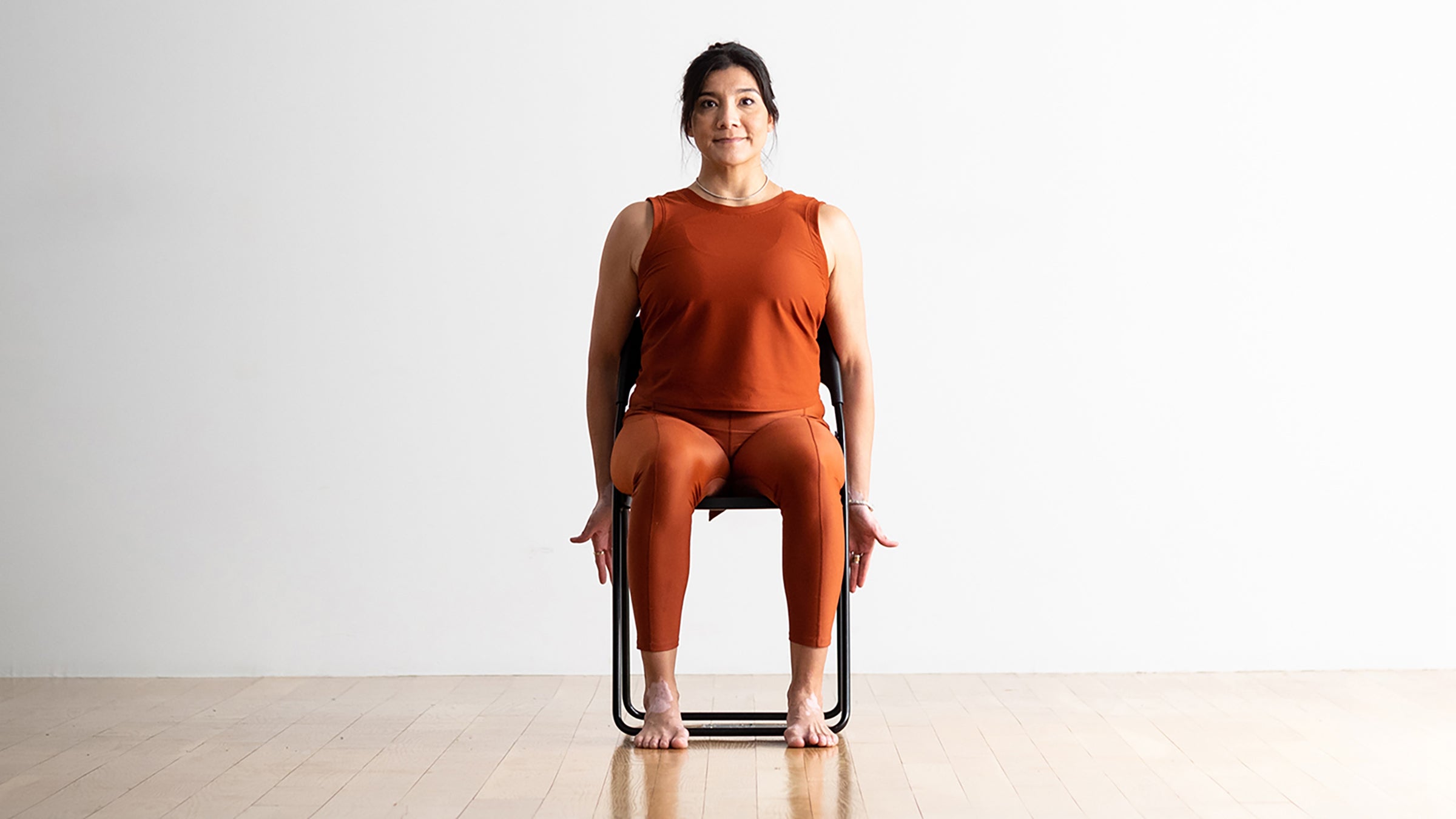 Woman demonstrating Mountain Pose variation in a chair