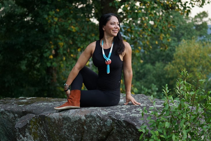 Kate Herrera Jenkins in black tights and rust colored boots does a spinal twist