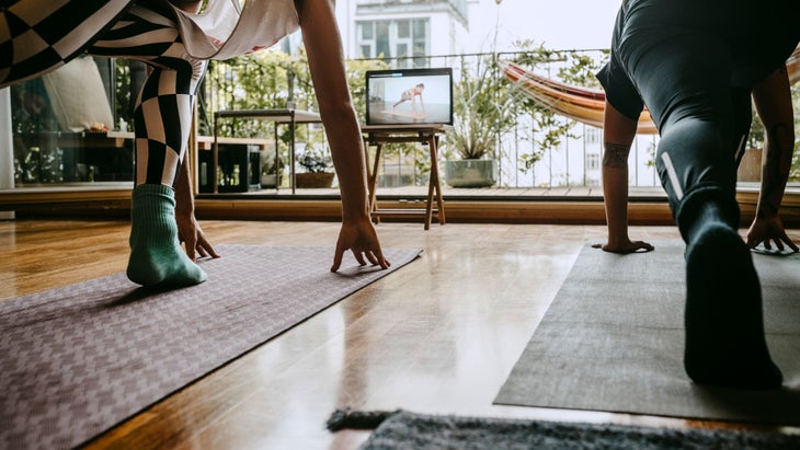 Two people practice yoga with a YouTube video