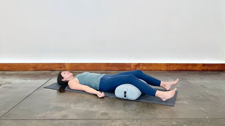 A person demonstrates a restorative Savasana (Corpse Pose) in yoga