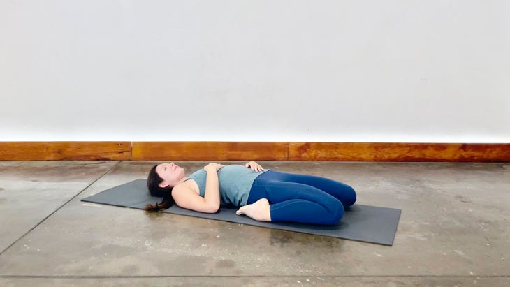 A person demonstrates Reclining Hero Pose (Supta Vajrasana) in yoga